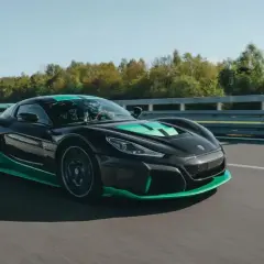 Czarny Rimac Nevera z zielonymi akcentami pędzi po torze, demonstrując swoją moc w przyspieszeniu 0-100 km/h.