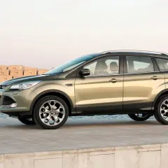 Złoty Ford Kuga stoi na betonowym molo, z morzem i falochronami w tle.