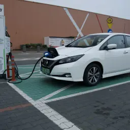 Biały Nissan Leaf ładuje się na stacji Greenway. Długi zasięg tego elektryka pozwala na swobodne podróżowanie.