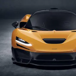 Pomarańczowy McLaren W1 z czarnym dachem i detalami z włókna węglowego, gotowy do jazdy.